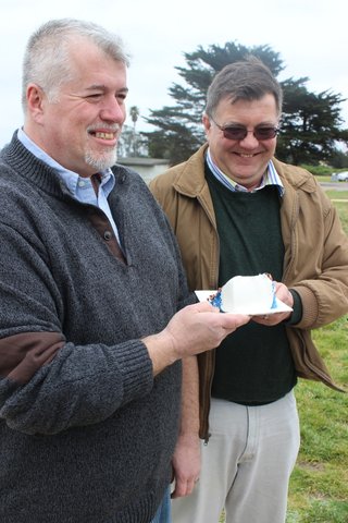 The newlyweds smile while sharing a piece of wedding cake.
